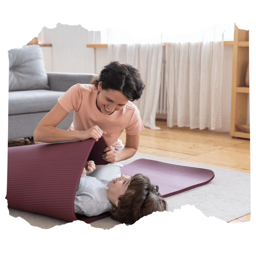 Mum rolling her child in a yoga mat, laughing together.